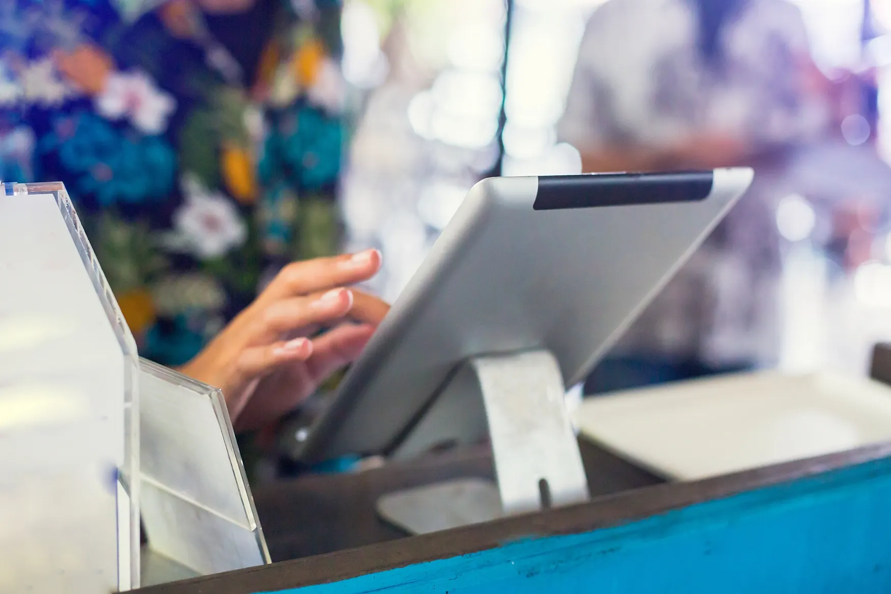 tablet on stand on register block with someone typing on touchscreen