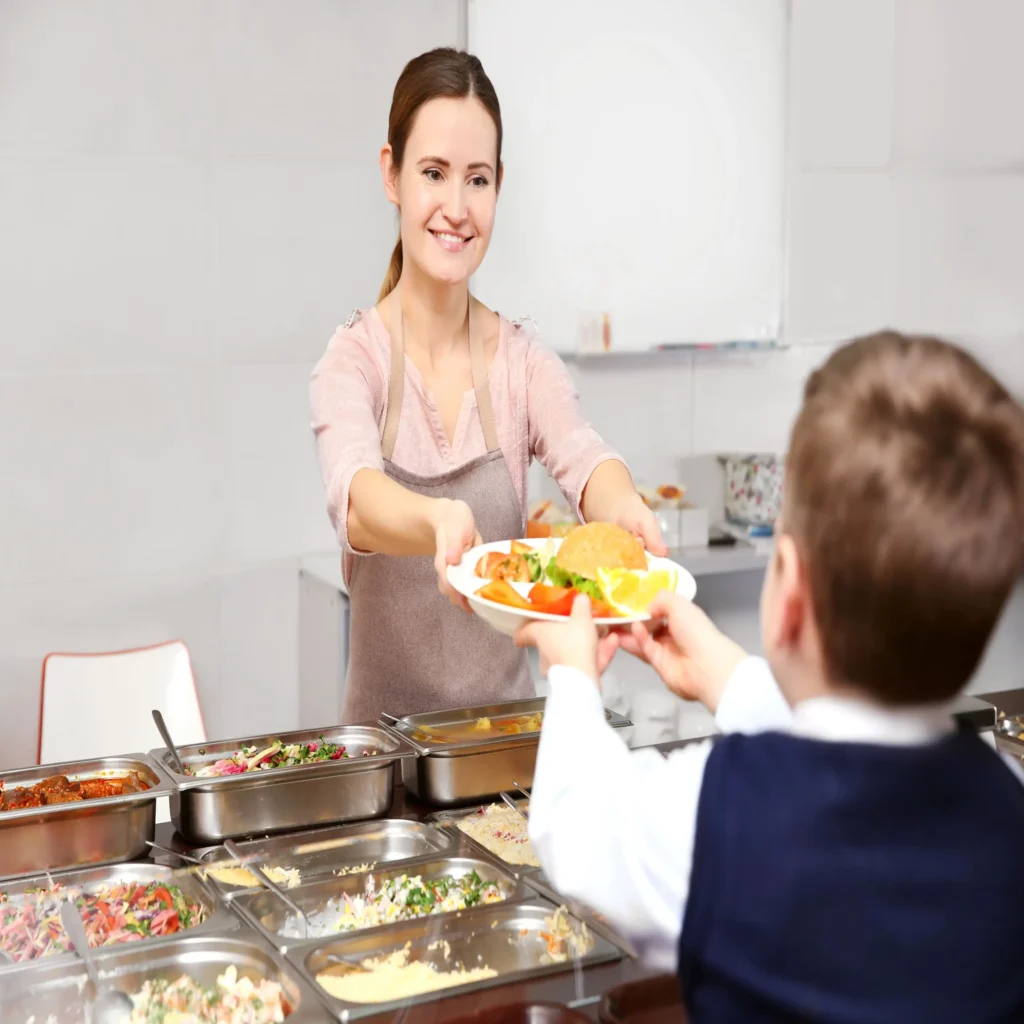 canteen staff handing out lunch to kid