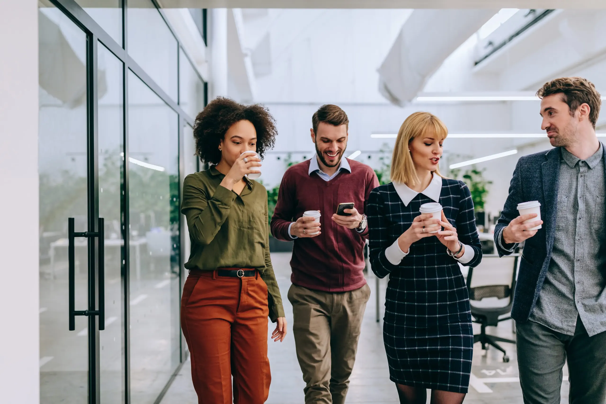colleagues in office building walking together with cups in hands